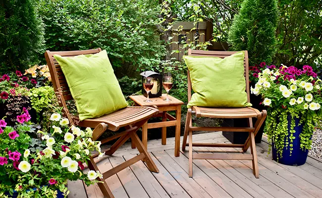 Wooden deck in garden with furniture.