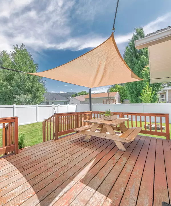 Deck Building In Castle Rock, CO Wooden deck with deck railing with a sunshade over the table with bench seats